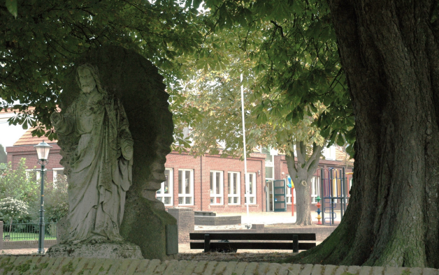 Afb.7. Heilig Hartbeeld aan de rugzijde van het Mariabeeld met op de achtergrond de huidige  basisschool ’t Scathe’ (foto) Hein Janssens).